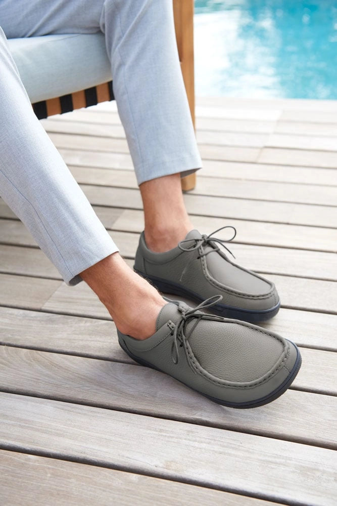 Mann trägt graue Freizeitschuhe neben einem Pool auf Holzboden