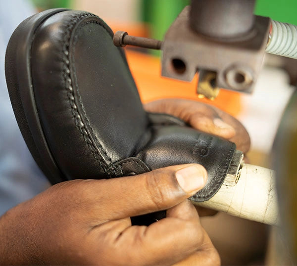 Nahaufnahme eines handgefertigten Lederschuhs in der Produktionsphase mit Nähen von Details in einer Werkstatt