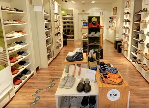 Innenansicht eines Schuhladen mit verschiedenen Schuhmodellen auf Regalen und Tischen