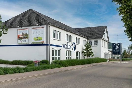 Das Bild zeigt die Außenansicht eines weißen Gebäudes mit dem Logo von Walter, einem Fachgeschäft, bei strahlend blauem Himmel.